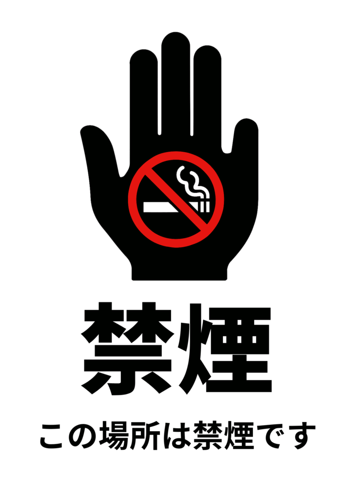 黒い手のひらの中に禁煙マークが配置され、「禁煙」「この場所は禁煙です」と日本語で書かれた注意喚起の張り紙。